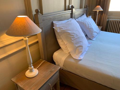 ブザンソンにあるL'Annexe Apparthôtel du 11 A, 4 étoilesのベッド(白い枕、テーブルの上のランプ付)