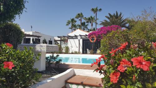 una casa con piscina y algunas flores en La Concha del Mar, en Corralejo