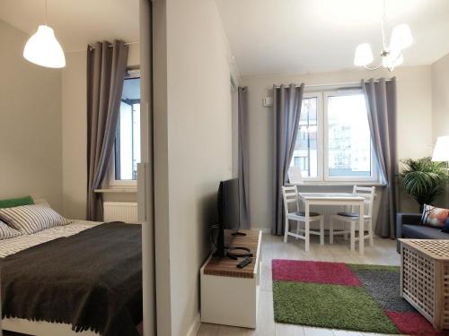 a bedroom with a bed and a table with a tv at Airport Residence Green in Warsaw