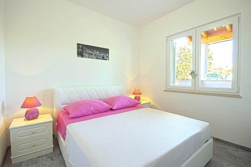 ein Schlafzimmer mit einem Bett mit rosa Kissen und einem Fenster in der Unterkunft *Amazing modern apartment with 2 bedrooms* in Vodnjan