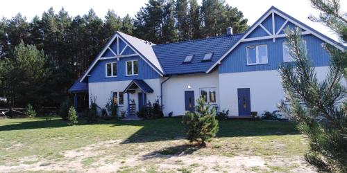 a blue and white house with a yard at Niebieski dom in Białogóra