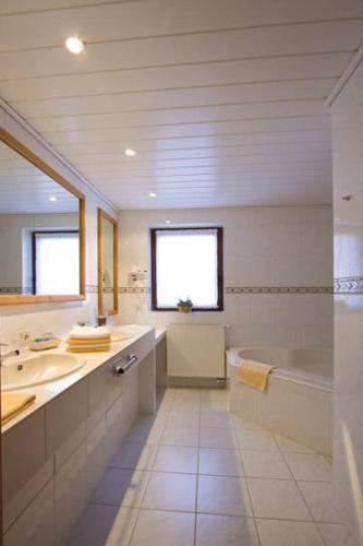 a white bathroom with a tub and a sink and a bath tub at Berghotel Habbel und die Welt kann warten in Cobbenrode