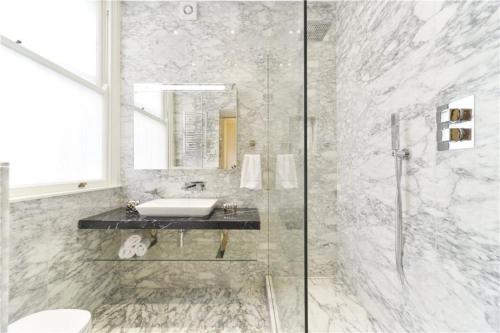 a bathroom with a sink and a glass shower at Beautiful 1 Bedroom Apartment Ovington Square in London