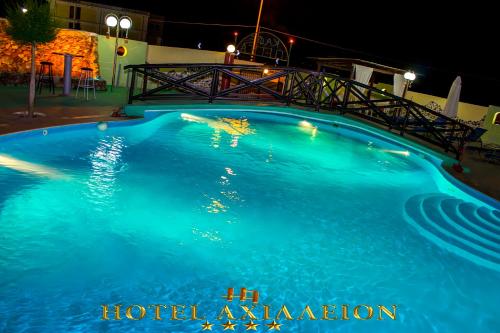 a large blue swimming pool at night at Achillion Palace in Kalambaki
