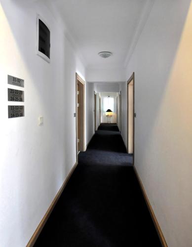 an empty hallway with white walls and a long black carpet at Artunc Hotel Bodrum in Bodrum City