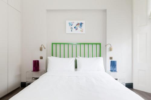 a bedroom with a white bed with a green headboard at Beautiful 1 Bedroom Apartment Ovington Square in London