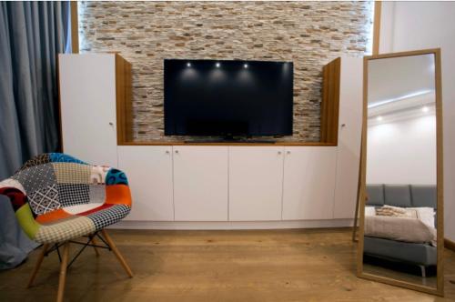 a living room with a tv and a chair and a mirror at Luxury apartment in the heart of Mykonos town in Mýkonos City
