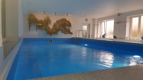 a large swimming pool with blue water in a room at Hotel-Pension Haus Hubertus in Borkum