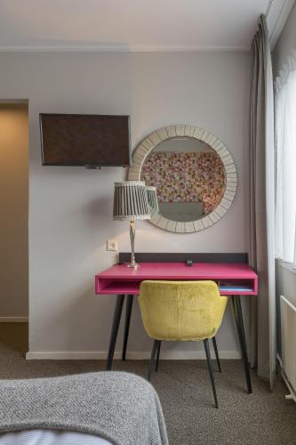 a pink desk with a lamp and a mirror at Hotel Op Diek in Den Hoorn