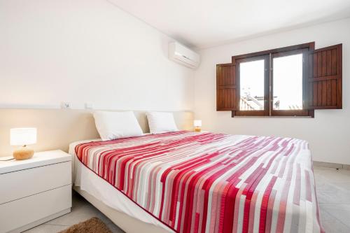 a white bedroom with a bed with a striped blanket at Loft 1º de Maio in Tavira