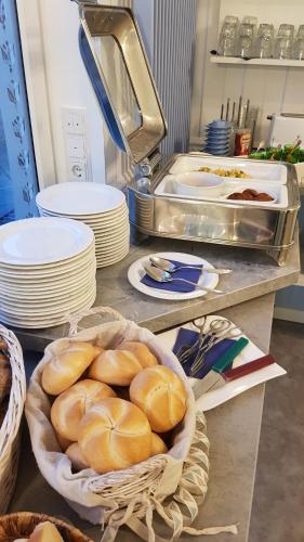 a table with plates and a basket of bread at Hotel-Pension Haus Hubertus in Borkum