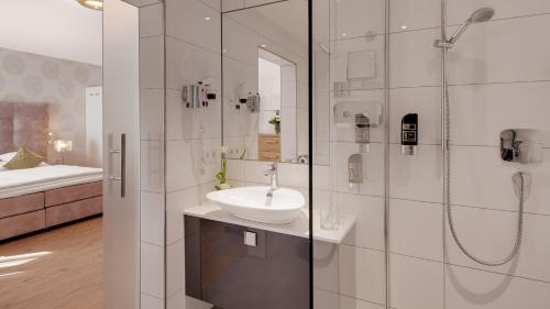 a white bathroom with a sink and a shower at Hotel Moselauen in Bernkastel-Kues