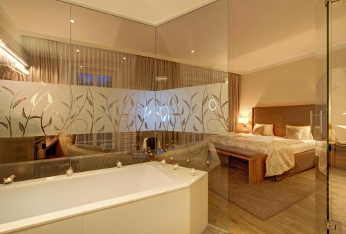 ein Badezimmer mit einer Badewanne und ein Schlafzimmer mit einem Bett in der Unterkunft Hotel Schneeberghof in Puchberg am Schneeberg