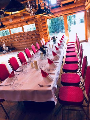 a long table with red chairs in a room at Villa Audruvis in Joniškis