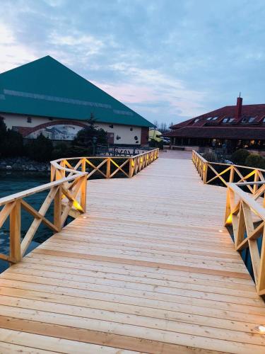 a wooden boardwalk leading to a building on the water at Villa Audruvis in Joniškis