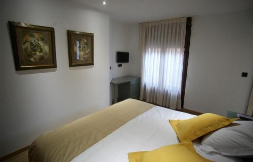 a bedroom with a bed with white sheets and yellow pillows at Boutique Hotel Castilla in Soria