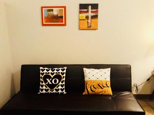 a black couch with two pillows in a living room at The Sentinel Residences Suite in Manila