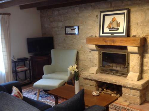 a living room with a fireplace and a chair at Brittany Vacation Rental in Plomelin