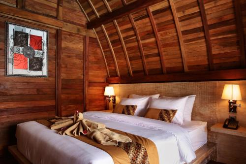 two beds in a room with wooden walls at Poedja Villa Jimbaran in Jimbaran