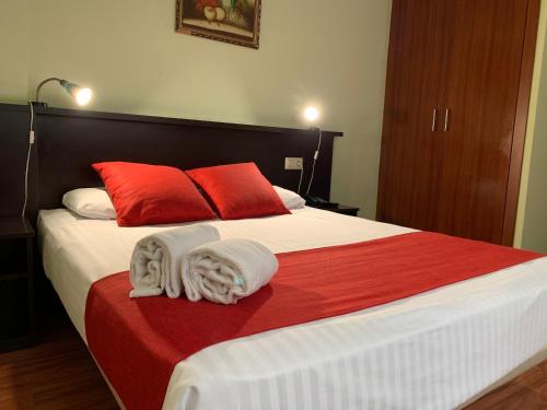 a bedroom with a large bed with red and white pillows at Hostal Hotil Coruña Centro in A Coruña