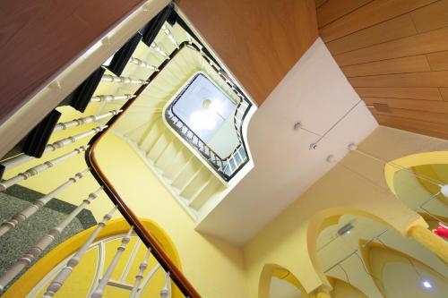 un escalier en colimaçon avec des chaises jaunes et une fenêtre dans l'établissement Hotel Reichshof garni, à Schwerte