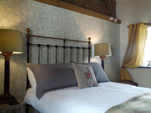 a bedroom with a bed with white sheets and two lamps at Castle Street Cottage in Ruthin