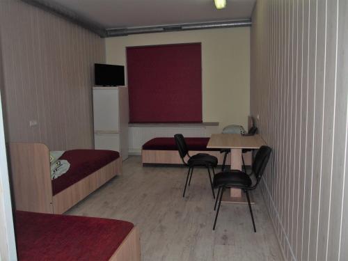 a small room with a bed and a table and chairs at Hostelis Laurita in Kaunas
