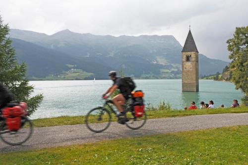 two people riding bikes on a path next to a lake at Garni Marianne in Malles Venosta