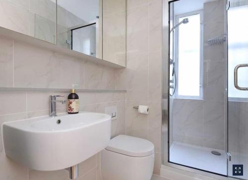 a bathroom with a sink and a toilet and a shower at 2 Bedroom Apartment just off Kings Road in London