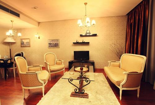a living room with chairs and a table and a tv at Tirana International Hotel & Conference Center in Tirana