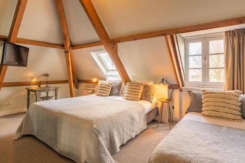 a bedroom with two beds and a tv and windows at Boutique Hotel Het Scheepshuys in Breda