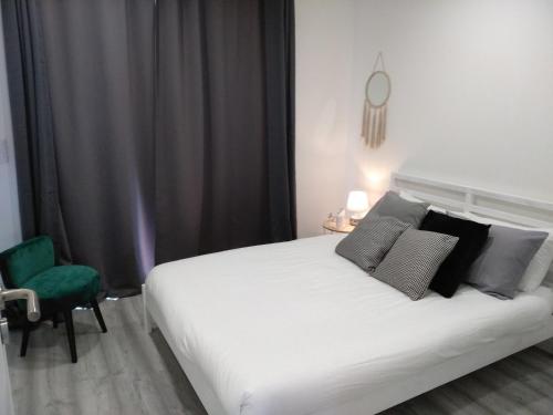 um quarto com uma cama branca e uma cadeira verde em Casas do Pedro T1 em Vila Praia de Âncora