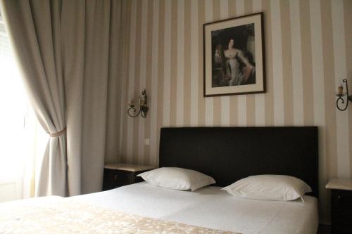 uma cama com duas almofadas e uma fotografia na parede em Brasilia em Lisboa