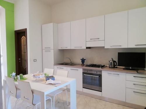 a kitchen with white cabinets and a white table with chairs at Stella di Mare in La Spezia