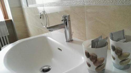 a bathroom sink with two cups and a faucet at Oasi delle Gazze in Genga