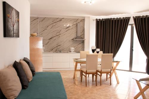 - un salon avec un canapé et une table avec des chaises dans l'établissement Flora Apartments Sarande, à Saranda