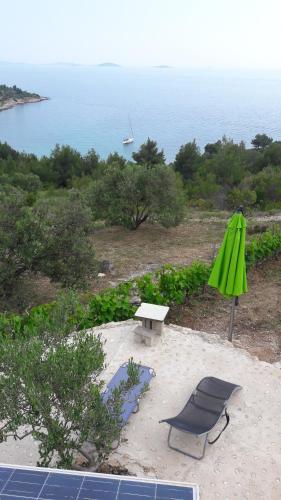 a green umbrella and a table and a chair at Kuća Paradise- Robinson in Murter