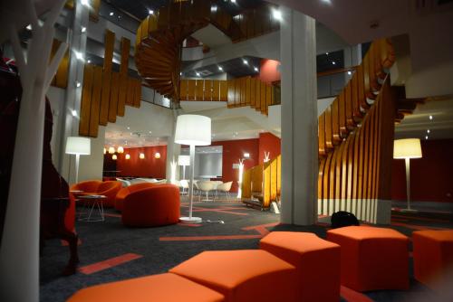 a large room with orange chairs and stairs at ibis Styles Poitiers Centre in Poitiers