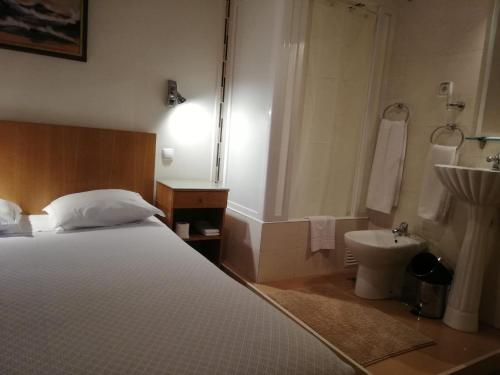 um quarto com uma cama e uma casa de banho com um lavatório em Brasilia em Lisboa
