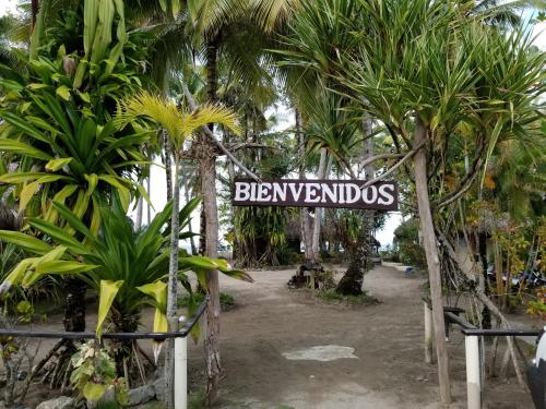 a sign in the middle of a bunch of palm trees at Playa Paraiso en Magante in La Yagua