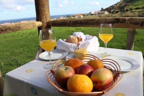 um cesto de maçãs e laranjas numa mesa com copos de vinho em Casas da Quinta em Santa Cruz das Flores