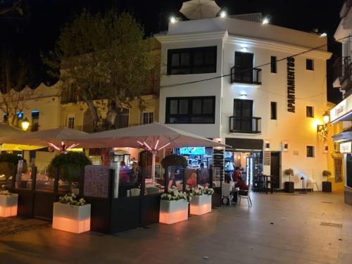 un bâtiment avec des tables et des parasols dans une rue la nuit dans l'établissement Apartamentos Kronox, à Nerja
