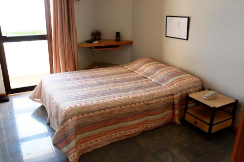 1 cama pequeña en un dormitorio con mesa en Apart Hotel Atlantic City Salvador, en Salvador