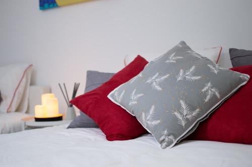 Cama con almohadas rojas y almohada gris en Apartamentos Océanos, en Málaga