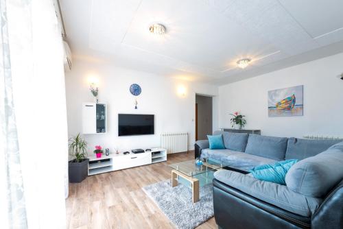 a living room with a blue couch and a tv at luxury apartment with garden jacuzzi and wellness in Trogir