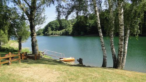 a boat sitting on the shore of a lake at Maison Lac de Pareloup -LES PIEDS DANS L'EAU- in Arvieu