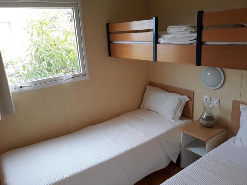 two beds in a small room with a window at A Deolinda in Santiago do Cacém