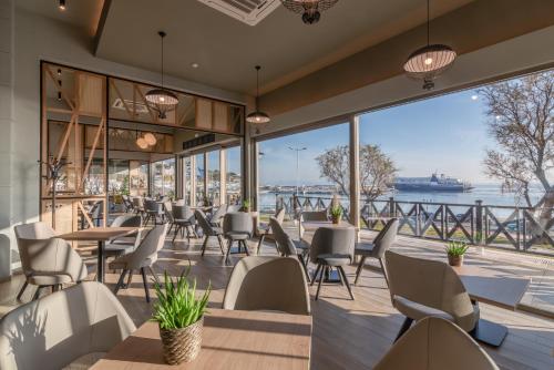 a restaurant with tables and chairs and a view of the water at Hotel Avra by Smile hotels - Free Airport Shuttle in Rafina