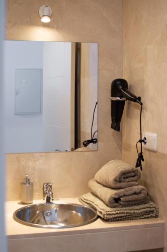 a bathroom with a sink and a mirror and towels at Apartamentos Océanos in Málaga
