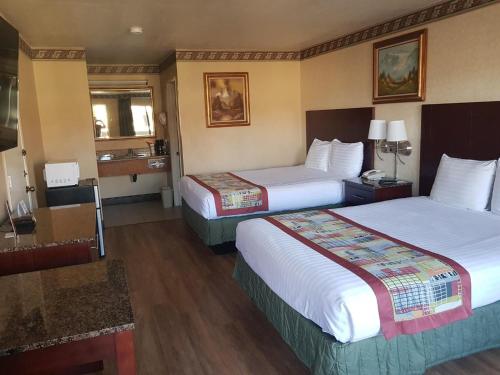 a hotel room with two beds and a bathroom at Travelodge by Wyndham Costa Mesa Newport Beach Hacienda in Costa Mesa